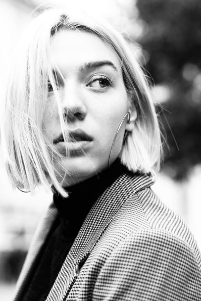 Outdoor urban female portrait, black and white. Fashion model. Young woman posing in Milan streets. Beautiful caucasian girl with blond hair walking in city. - Foto, immagini