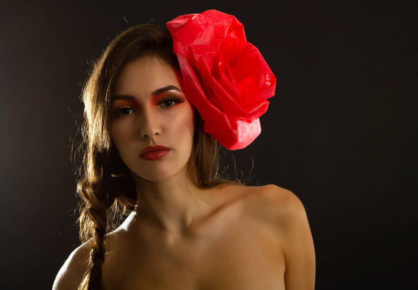 Vintage portrait of fashion glamour girl with red flower in her hair, over black. Studio shot. Spanish Carmen style - Фото, изображение