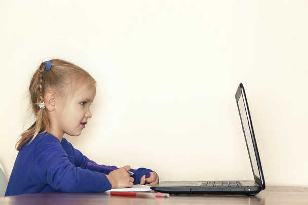 Aufmerksam blickt das kleine Mädchen auf den Computermonitor. Das Kind kommuniziert online - Foto, Bild
