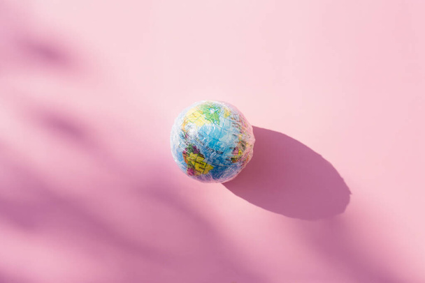 Planet Earth in wrap polyethylene plastic. The globe and global pollution by plastic. Minimal enviromental concept. Flat flat, top view - Φωτογραφία, εικόνα