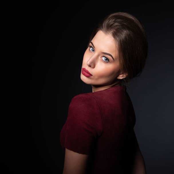 Portrait of attractive blue-eyed young woman over black background. Amazing girl with perfect makeup wearing elegant deep red dress. Beauty and fashion - Fotografie, Obrázek