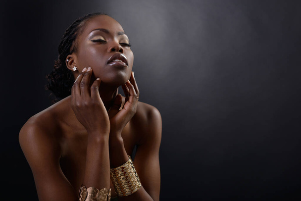 Gorgeous young african american woman looking down st copy space, over black background. Beauty portrait of charming girl with clean skin and eyes closed with pleasure, studio shot - Foto, Imagem
