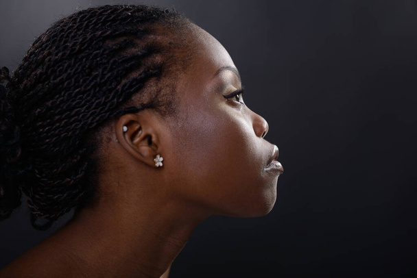 Profile of gorgeous young african american woman, over black background. Beauty portrait of charming girl with clean skin, studio shot - Fotografie, Obrázek