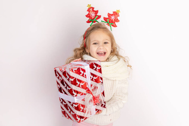 девочка держит красный подарок на белом изолированном фоне, место для текста - Фото, изображение