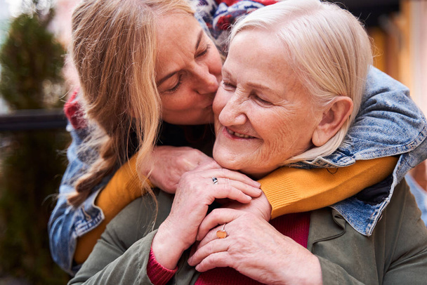 Woman kissing her elderly mother at the cheek - Foto, afbeelding