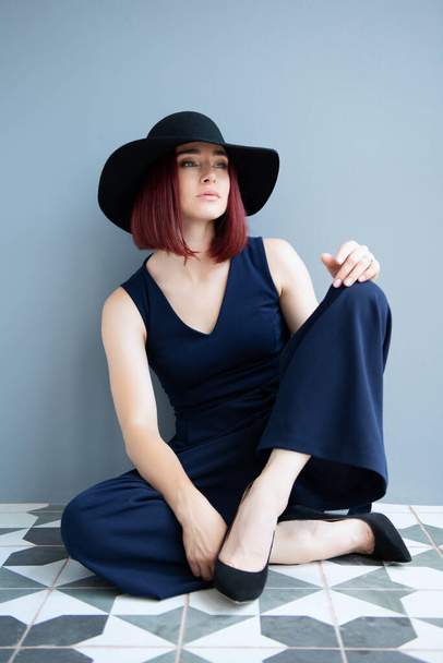 Fashion woman wearing deep blue clothes and black hat posing indoor  - Photo, Image