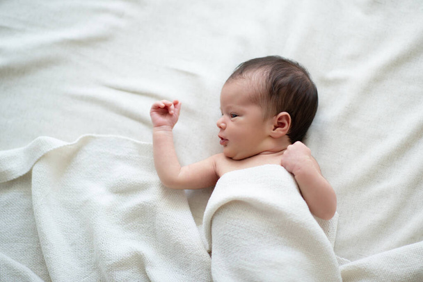 New born baby girl lying in bed on white sheets. Cute little kid's portrait - Foto, afbeelding