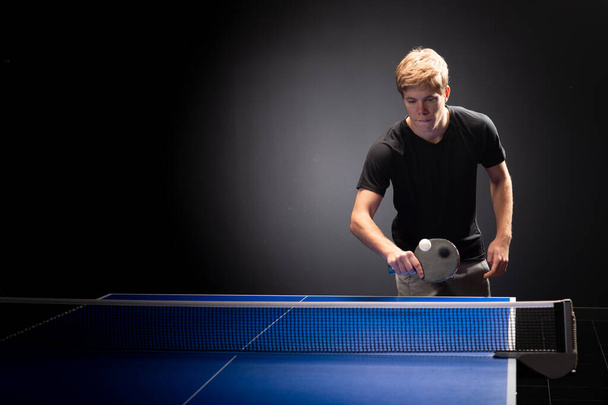 Retrato de jovem jogando tênis em fundo preto - Foto, Imagem