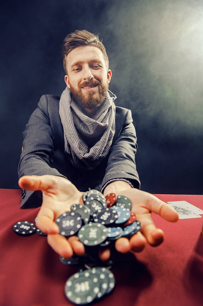 Happy stylish bearded Man in suit and scarf playing in dark casino, smoking cigar, drink whiskey - Fotoğraf, Görsel