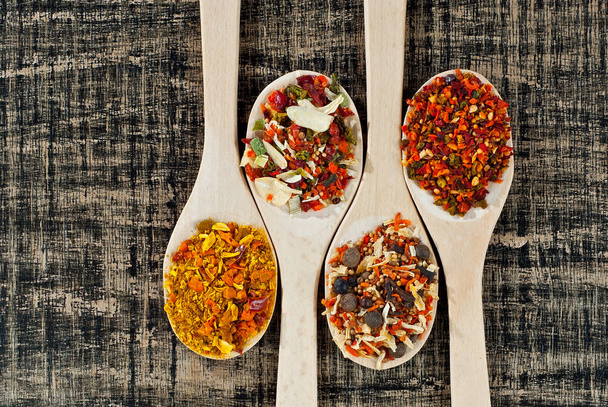 A mixture of various spices in a wooden spoon. Spices and seasonings on an old shabby board. Mix on a pile close up. Place for text and copy space near the spoon. - Фото, изображение