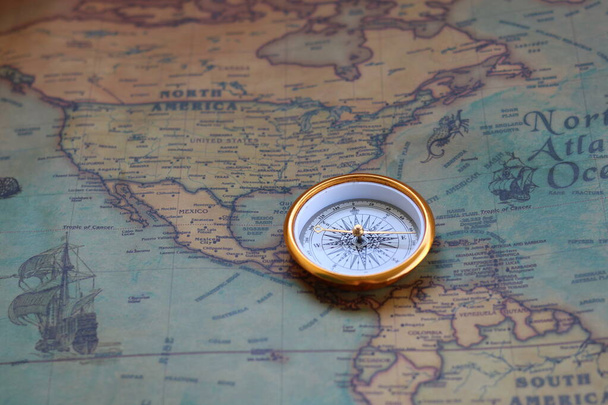 Classic round compass on old vintage map depicting North America and the United States of America as symbol of tourism with compass, travel with compass and outdoor activities with compass - 写真・画像