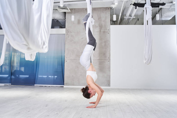 Woman practices aero anti-gravity yoga position - 写真・画像
