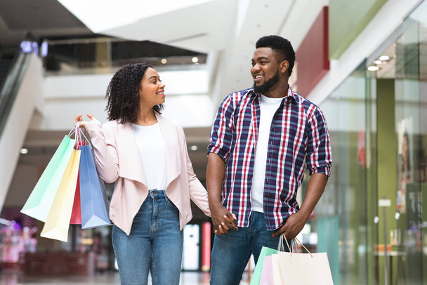 Glückliches schwarzes Shopaholic-Paar spaziert durch Kaufhaus und genießt das gemeinsame Einkaufen - Foto, Bild
