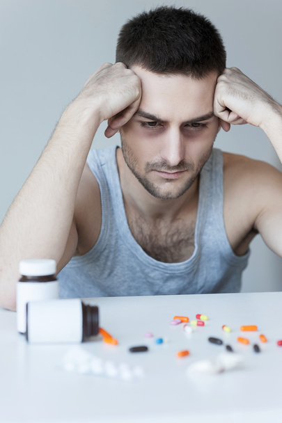 Frustrated young man looking at the pills - Foto, imagen