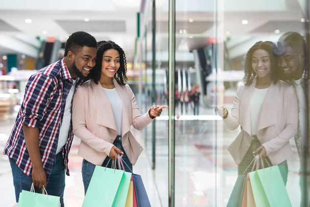 Cônjuges negros felizes gostando de fazer compras juntos no shopping, olhando para a mostra - Foto, Imagem