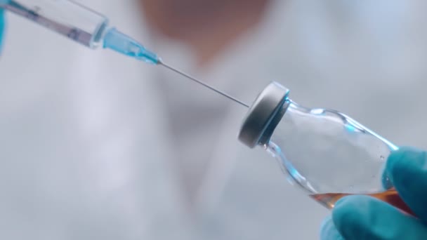 Close-up of doctors hands holding syringe with transparent solution and infusing in ampoul with red substance. Process of vaccine development, experimental researches in medical laboratory, potential - Footage, Video