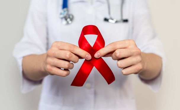Fita vermelha para SIDA e apoio do dia mundial hiv, de perto. Mão de médico feminino. - Foto, Imagem