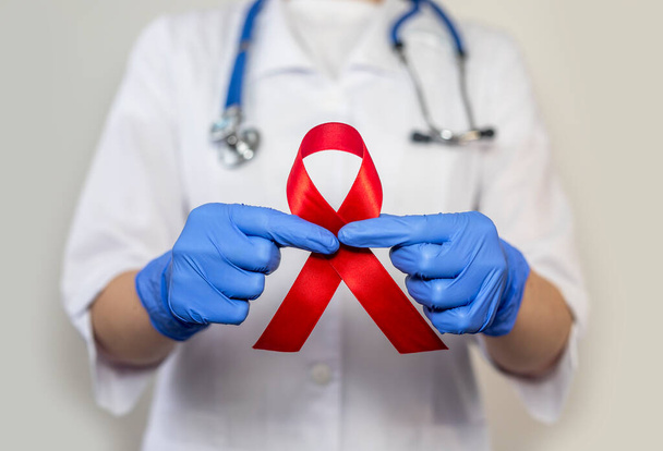 Red ribbon for aids and hiv world day support, close up. Hand of female doctor. - Foto, Imagem