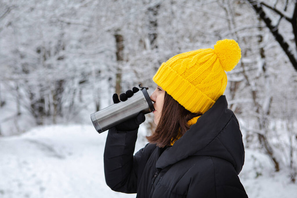 žena v zimním oblečení pití zahřát nápoj z plnitelný hrnek kopírovat prostor - Fotografie, Obrázek
