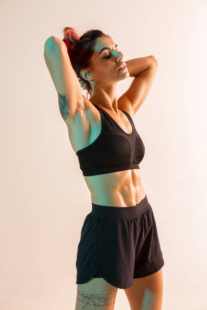 Athletic fit young girl in stylish black sportswear posing in studio - Fotoğraf, Görsel