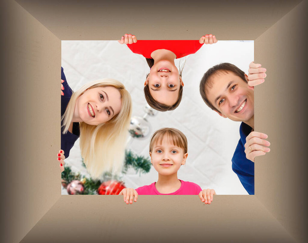 Glückliche Familie guckt in die Schachtel, guckt in eine Geschenkschachtel. Konzept von Urlaub, frohe Weihnachten, Urlaub und Familie. - Foto, Bild