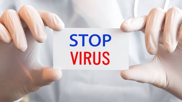 Arzt hält eine Karte mit dem Text STOP VIRUS in beiden Händen. Medizinisches Konzept, - Foto, Bild