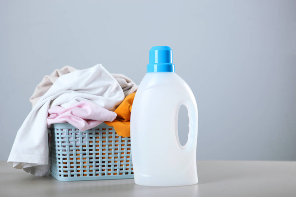 Botellas de detergente de lavandería y ropa en la mesa. Productos químicos para el hogar. Foto de alta calidad - Foto, imagen