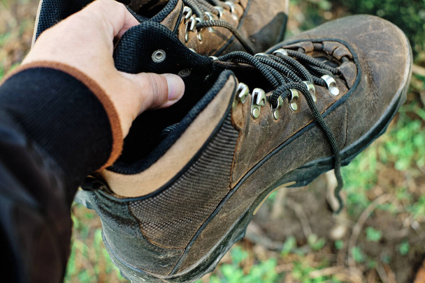 Oude vuile wandelschoenen met één hand - Foto, afbeelding
