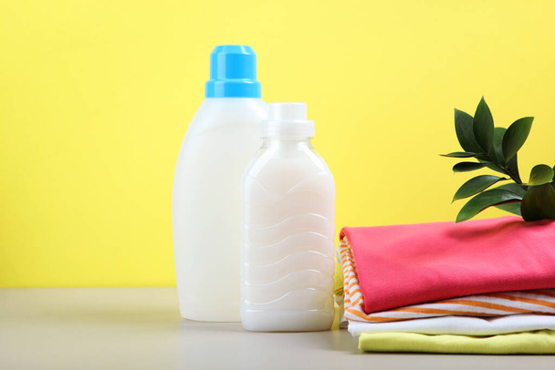 Waschmittelflaschen und Kleidung auf dem Tisch. Haushaltschemikalien - Foto, Bild