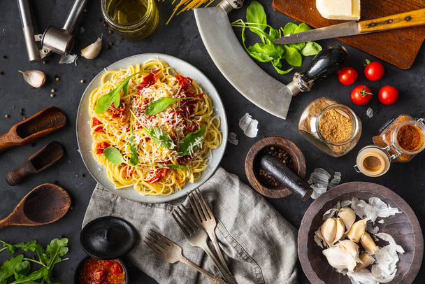 Italienisches Abendessen mit Pasta auf Keramikteller mit Zutaten auf schwarzem Hintergrund. Flache Ansicht. Ansicht von oben. - Foto, Bild