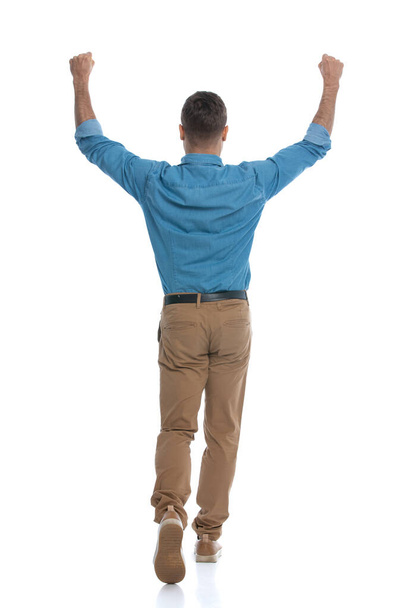 vista trasera de un tipo casual levantando el puño y alejándose sobre fondo blanco - Foto, Imagen