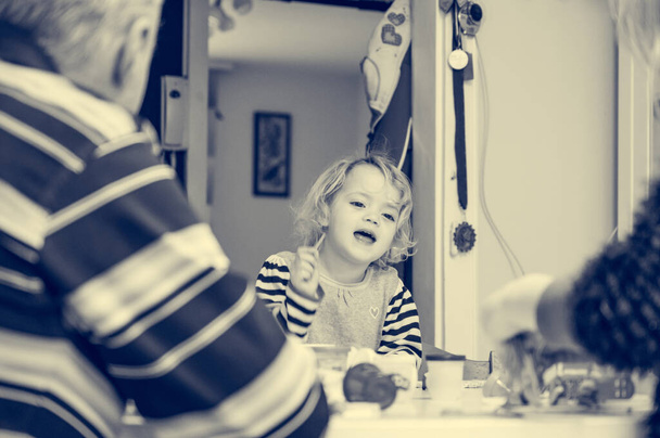 Cute girl gra z wielu kolorowych ciasta w otoczeniu nierozpoznawalnych członków rodziny. - Zdjęcie, obraz