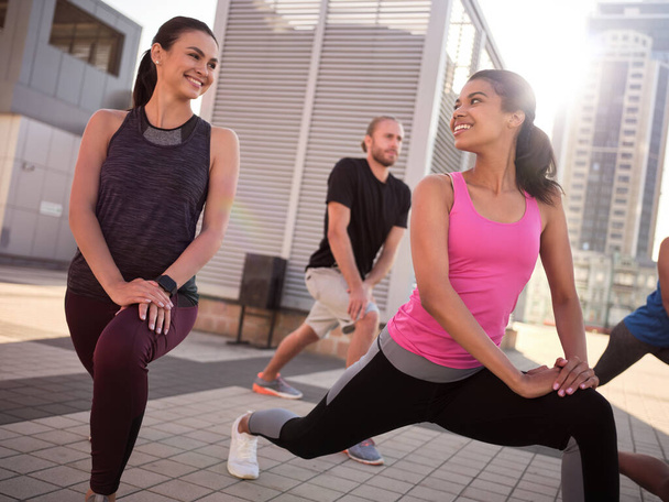 Smiling young girls doing lunges and talking to each other - Photo, Image