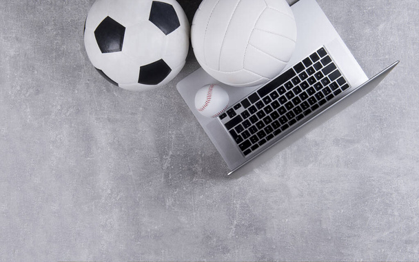 Fútbol, voleibol y pelota de béisbol y portátil gris sobre fondo gris. Concepto de entrenamiento en línea - Foto, Imagen