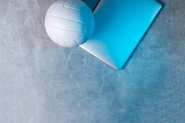 White Volleyball ball and grey laptop on grey background. Online workout concept - Photo, Image