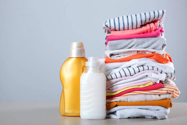 Μπουκαλάκια απορρυπαντικού ρούχων και ρούχα στο τραπέζι. Οικιακές χημικές ουσίες - Φωτογραφία, εικόνα