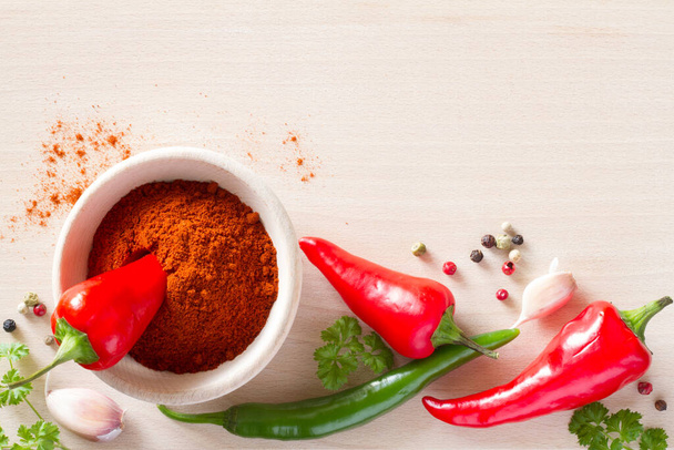 Whole and ground powder chili peppers on wooden kitchen board with spices - Fotó, kép