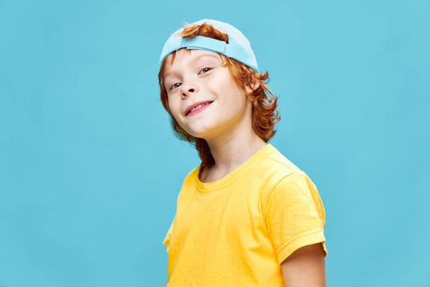 Sorrindo menino inclinando a cabeça para um lado azul boné moda diversão infância  - Foto, Imagem