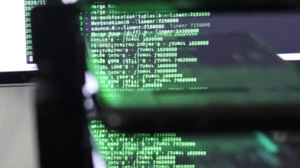 Groene computersoftware code bewegend op een zwarte monitor reflecteert op glas. Abstract computer hacken in proces met rack server base, dynamische tekst draait en stroomt op pc scherm. - Video