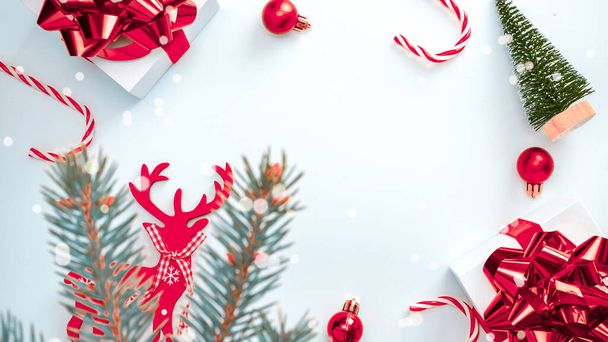2021 Białe pudełko z czerwoną wstążką, piłeczki noworoczne, cukierki i musujące światła w kompozycji świątecznej na białym tle dla kartki okolicznościowej. Dekoracja i kopiowanie miejsca na tekst - Zdjęcie, obraz