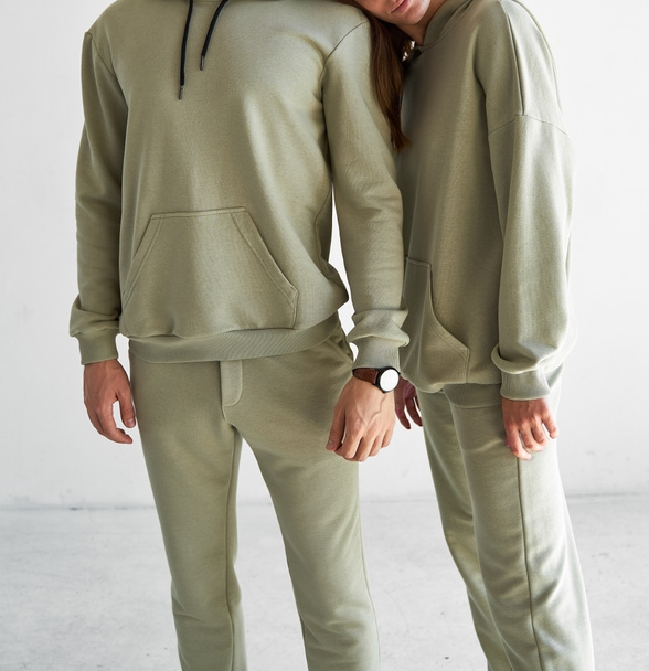 Pari seisoo yhdessä yksivärisissä urheiluvaatteissa. mies ja nainen pukeutuu vaaleanvihreisiin vaatteisiin - Valokuva, kuva