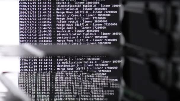 Biały kod oprogramowania komputerowego poruszający się na czarnym monitorze odbija się na szkle. Abstrakcyjne hacking komputera w procesie z bazy serwera rack, dynamiczny tekst uruchomiony i płynący na ekranie komputera. - Materiał filmowy, wideo