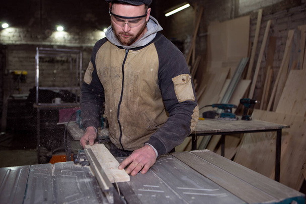worker processes a wooden Board on a circular machine - Φωτογραφία, εικόνα