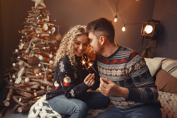 Elegant couple sitting at home near christmas tree - 写真・画像