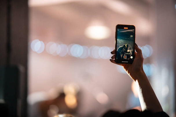 Человек крупным планом записи видео со смартфона во время концерта. - Фото, изображение