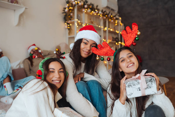 Мультиэтническая группа друзей в шляпах Санта-Клауса с подарками в руках. - Фото, изображение