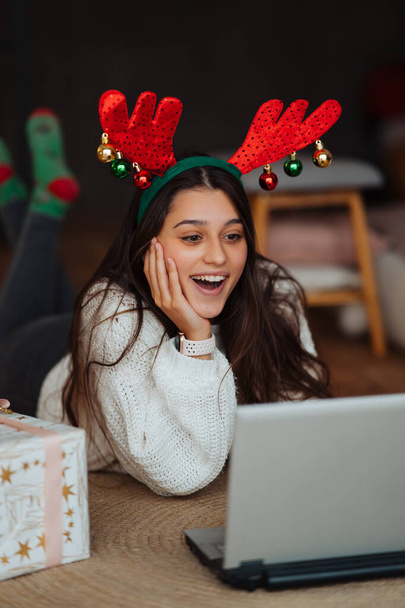 Female with antlers while speaking with online friend on laptop - Photo, Image
