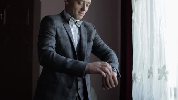 Mann im Anzug zieht Armbanduhr an. Bräutigam kleidet sich. Junger männlicher Geschäftsmann wartet auf Treffen - Filmmaterial, Video