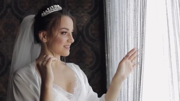 Braut im Boudoir-Kleid am Fenster. Hochzeitsvorbereitungen. Frau in Nachthemd und Schleier - Filmmaterial, Video
