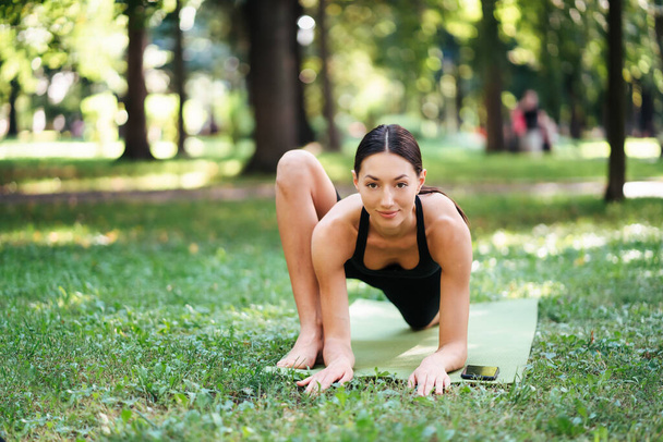 Sportliche junge Frau macht morgens Yoga im Park. - Foto, Bild